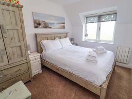 A bedroom with a bed and wardrobe at Farne Cottage Beadnell