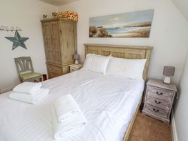 A bedroom with a bed and wardrobe at Farne Cottage Beadnell
