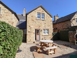 An outdoor area with a stone house and a picnic table at Russet in Lucker