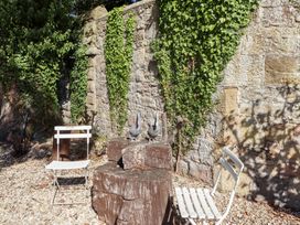 A garden with a stone wall and seating at Russet in Lucker