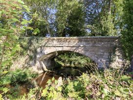 A stone bridge over a stream surrounded by trees at Russet in Lucker