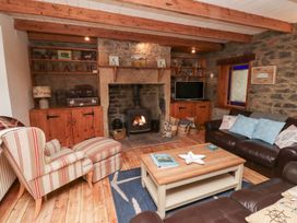 A living room with stone walls wooden beams a fireplace armchair and leather sofas at Hares Form in Seahouses