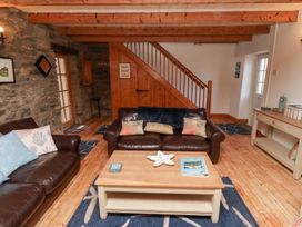 A living room with leather sofas wooden coffee table and staircase with stone wall at Hares Form in Seahouses