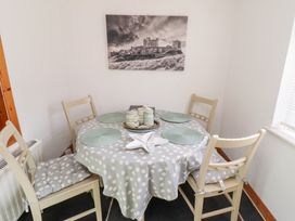 A dining area with a round table covered with a polka dot tablecloth four chairs and a black and white landscape picture on the wall at Hares Form in Seahouses