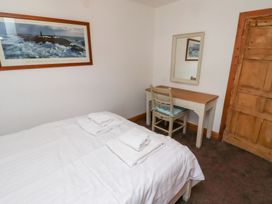 A bedroom with a bed with white linens and folded towels a desk with a chair and a mirror and a wooden door at Hares Form in Seahouses