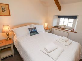 A bedroom with a double bed two bedside tables with lamps a window and folded towels on the bed at Hares Form in Seahouses