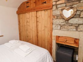 A bedroom with a bed with folded towels wooden wardrobe and stone wall with a heart shaped mirror at Hares Form in Seahouses