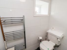 A bathroom with a toilet paper holder radiator and a small window at Hares Form in Seahouses