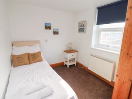 A bedroom with a single bed side table lamp radiator and window at Hares Form in Seahouses