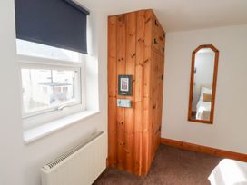 A room corner with a blue window blind a radiator a wooden wardrobe and a wooden framed mirror on the wall at Hares Form in Seahouses