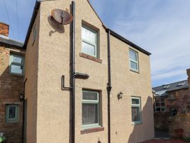 An exterior view of a beige stucco house with green framed windows and black rain gutters at Hares Form in Seahouses