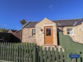 A cottage with a wooden door and fenced garden at Avocet Cottage - Lucker Steadings, Lucker