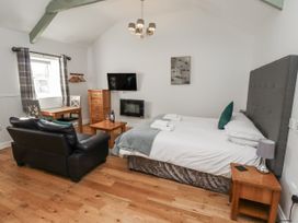 A bedroom with a bed, sofa, and dining table at Avocet Cottage - Lucker Steadings Lucker