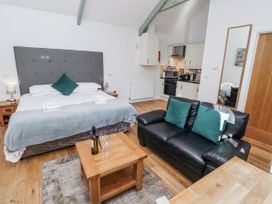 A bedroom with a bed and a kitchen area at Avocet Cottage - Lucker Steadings, Lucker