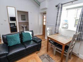 A living room with a sofa and dining table at Avocet Cottage - Lucker Steadings in Lucker