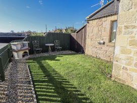 A garden with table and chairs next to a barbecue at Avocet Cottage - Lucker Steadings Lucker