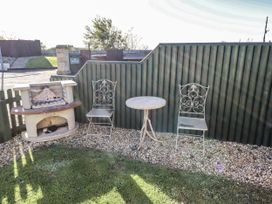 A garden with a grill, table, and chairs at Avocet Cottage - Lucker Steadings Lucker