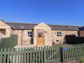 A cottage exterior with stone walls and patio area at Dunlin Cottage - Lucker Steadings in Lucker