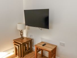 A living room with a television and lamp at Dunlin Cottage - Lucker Steadings in Lucker