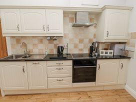 A kitchen with cabinets, sink, and appliances at Dunlin Cottage - Lucker Steadings Lucker