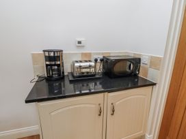 A kitchen counter with coffee maker, toaster, and microwave at Dunlin Cottage - Lucker Steadings in Lucker