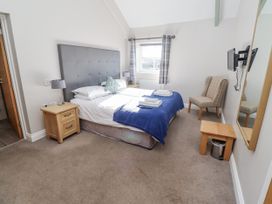 A bedroom with a bed and an armchair at Dunlin Cottage - Lucker Steadings Lucker