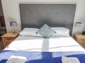 A bedroom with a bed and bedside tables at Dunlin Cottage - Lucker Steadings Lucker