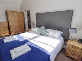 A bedroom with a bed and wooden furniture at Dunlin Cottage - Lucker Steadings Lucker