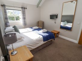 A bedroom with a bed, lamp, and television at Dunlin Cottage - Lucker Steadings Lucker