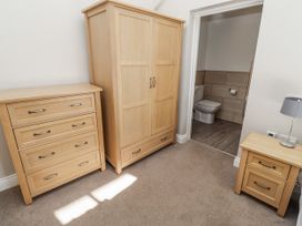 A bedroom with furniture including a wardrobe and chest of drawers at Dunlin Cottage - Lucker Steadings in Lucker
