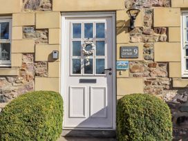 An entrance with a front door and bush at Dunlin Cottage in Bamburgh