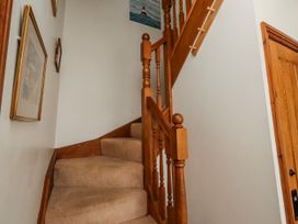 A staircase with a wooden handrail and framed artwork at No9 Budle Sands in Bamburgh