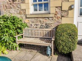 A bench beside a bush and stone wall at No9 Budle Sands in Bamburgh