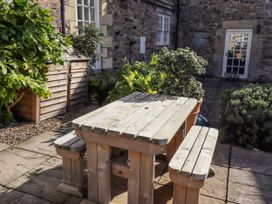 A wooden table and benches in a garden at No9 Budle Sands in Bamburgh