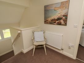 A landing area with a chair and painting at The Beach Hut in Beadnell