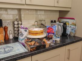 A kitchen counter with a cake, kettle, and various food items at Number Seventeen Amble