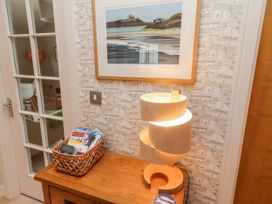 A hallway with a lamp and a basket of books at Cuddy's Holm in Seahouses
