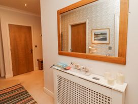 A hallway with a mirror and radiator cover at Cuddy's Holm in Seahouses