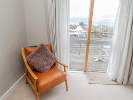 A living room with a chair and door leading to the balcony at Cuddy's Holm in Seahouses