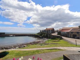 A view of a harbour with boats and houses at Coble Cottage in Craster