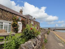 An outdoor area with stone walls and flowers at Coble Cottage in Craster