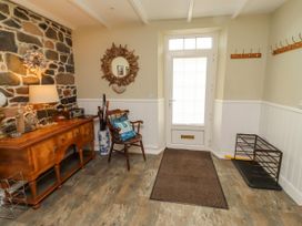 An entryway with a stone wall and a chair at Coble Cottage in Craster