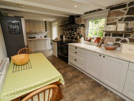 A kitchen with cabinets and a dining table at Coble Cottage Craster
