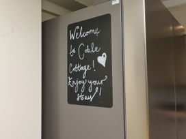 A welcome note on a chalkboard attached to a refrigerator at Coble Cottage in Craster