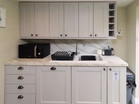 A kitchen with cabinets, sink, microwave, and dish rack at Coble Cottage, Craster