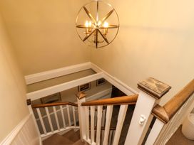 A staircase with a chandelier and framed pictures at Coble Cottage in Craster