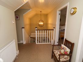 A landing with a staircase and light fixture at Coble Cottage Craster