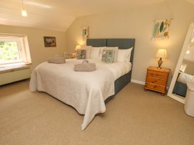 A bedroom with a large bed and bedside table at Coble Cottage Craster