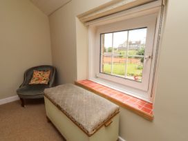 A room with a chair and an ottoman near a window at Coble Cottage Craster