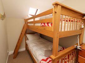A bunk bed with a ladder in a bedroom at Coble Cottage Craster